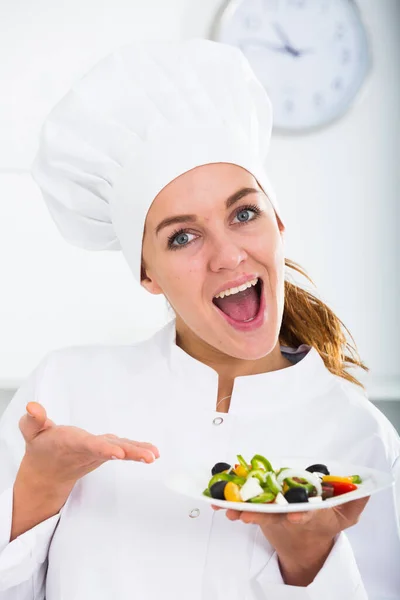 幸せな若い女性の肖像画栗色の髪キッチンでサラダを示しています — ストック写真