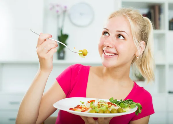 楽しいです大人ブロンド女の子食べるサラダ室内 — ストック写真