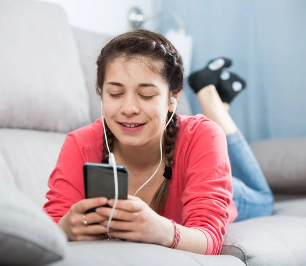 Νεαρή Κοπέλα Ελέγχει Τηλέφωνό Της Και Ακούει Μουσική Στο Σπίτι — Φωτογραφία Αρχείου