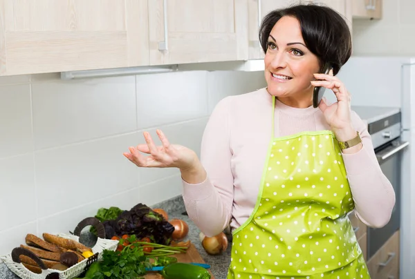 Χαρούμενη Γυναίκα Κουβεντιάζοντας Κάποιον Στο Τηλέφωνο Όπως Μαγείρεμα Δείπνο — Φωτογραφία Αρχείου