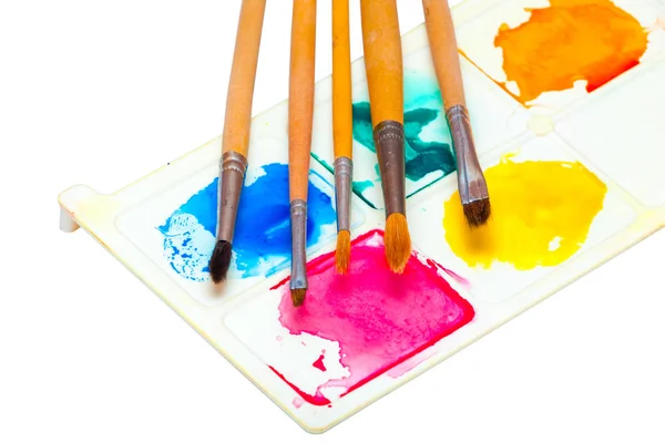 Five brushes for painting watercolors on a palette with paints on a white background — Stock Photo, Image