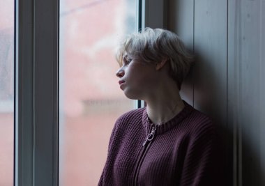 Pencerenin kenarında duran üzgün kız