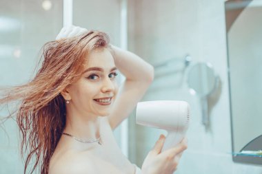 Kız saç kurutma makinesi saç kurutur.