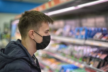 Maskeli bir Coronavirus süpermarketi alışveriş yapıyor.