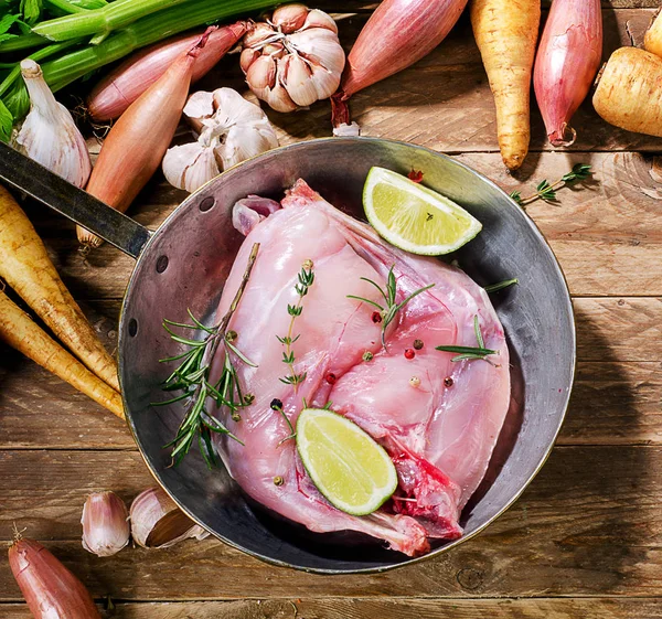 Rabbit legs in pan on wooden board. — Stock Photo, Image