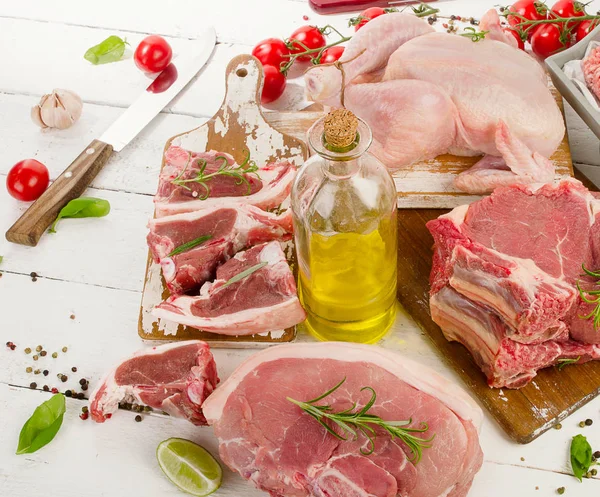 Different types of raw meat with fresh vegetables and herbs. — Stock Photo, Image