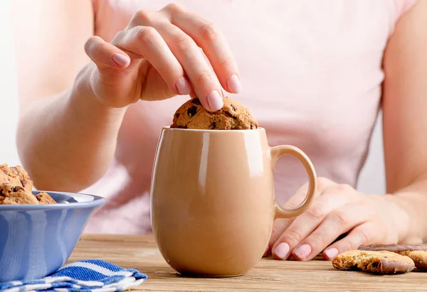 Vrouwelijke handen met thee kopje en cookie. — Stockfoto