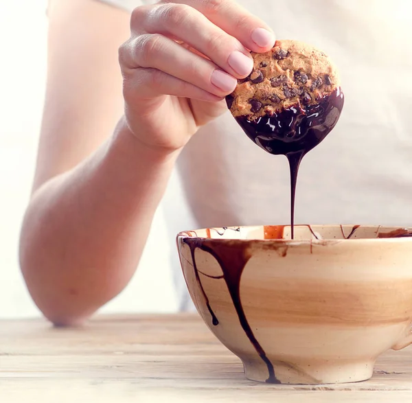 Hand-cookie in de gesmolten chocolade dippen — Stockfoto