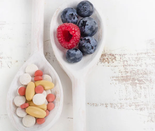 Fehér kanál tabletták és a friss bogyós gyümölcsök — Stock Fotó