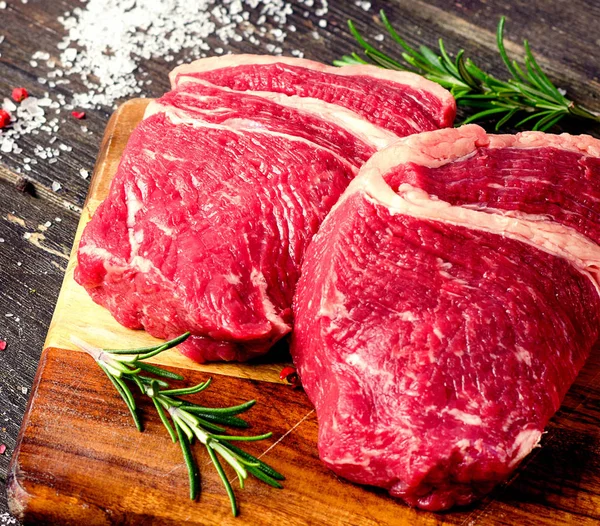 Raw beef steaks with rosemary — Stock Photo, Image