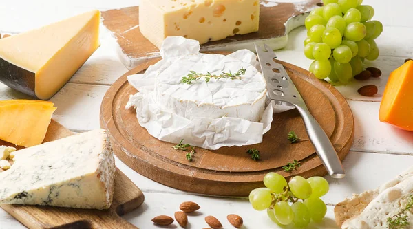 Cheeses on a white wooden board — Stock Photo, Image