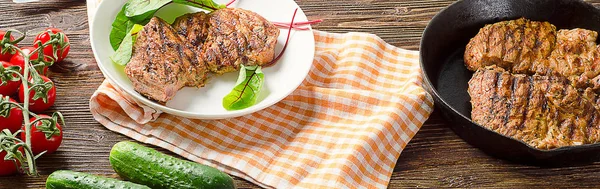 Steaks in der Pfanne auf einem dunklen Holztisch. — Stockfoto