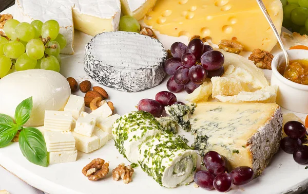 Platos de queso servidos con uvas, mermelada y frutos secos — Foto de Stock