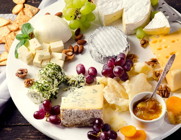 Platos de queso servidos con uvas, mermelada y frutos secos —  Fotos de Stock