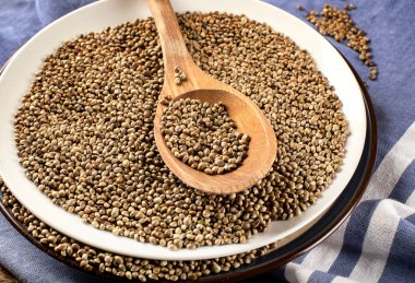 Kaşık kenevir tohumu mavi zemin üzerine beyaz seramik plaka ile yakın çekim  