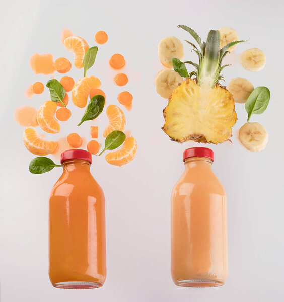 Вид свежих фруктов в бутылках из-под сока на белом фоне
