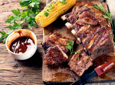 Pork ribs with corn on a wooden board. American food. View from above. clipart