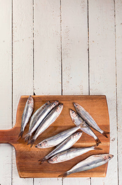 Fresh sprat fish on a white wooden background. Top view