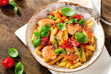 Penne makarna karides, domates ve eski ahşap bir masa üzerinde otlar ile. Üstten Görünüm. 