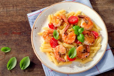 Penne makarna karides, domates ve eski ahşap bir masa üzerinde otlar ile. Üstten Görünüm. 