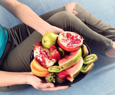 Genç kadın sağlıklı kahvaltı için taze meyve yeme. Yukarıdan görüntüleyin. Vegan sağlıklı beslenme kavramı