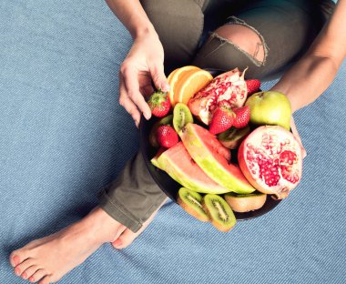 Genç kadın sağlıklı kahvaltı için taze meyve yeme. Yukarıdan görüntüleyin. Vegan sağlıklı beslenme kavramı
