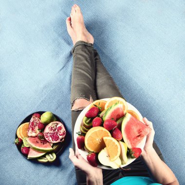 Genç kadın sağlıklı kahvaltı için taze meyve yeme. Yukarıdan görüntüleyin. Vegan sağlıklı beslenme kavramı
