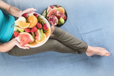 Genç kadın sağlıklı kahvaltı için taze meyve yeme. Yukarıdan görüntüleyin. Vegan sağlıklı beslenme kavramı