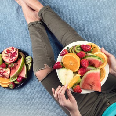 Genç kadın sağlıklı kahvaltı için taze meyve yeme. Yukarıdan görüntüleyin. Vegan sağlıklı beslenme kavramı