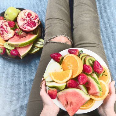 Genç kadın sağlıklı kahvaltı için taze meyve yeme. Yukarıdan görüntüleyin. Vegan sağlıklı beslenme kavramı