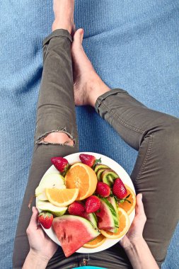 Genç kadın sağlıklı kahvaltı için taze meyve yeme. Yukarıdan görüntüleyin. Vegan sağlıklı beslenme kavramı
