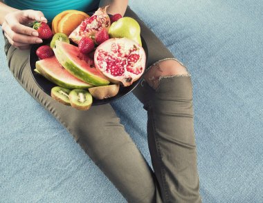 Genç kadın sağlıklı kahvaltı için taze meyve yeme. Yukarıdan görüntüleyin. Vegan sağlıklı beslenme kavramı