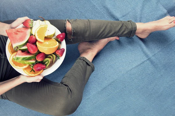 Genç kadın sağlıklı kahvaltı için taze meyve yeme. Yukarıdan görüntüleyin. Vegan sağlıklı beslenme kavramı