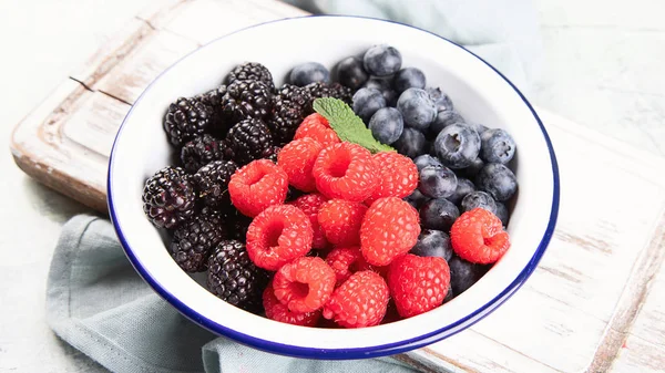 Different kinds of fresh berries mix on wooden surface