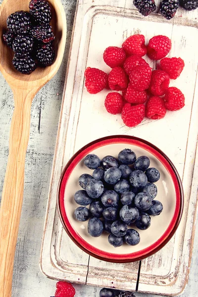 Different kinds of fresh berries mix on wooden surface