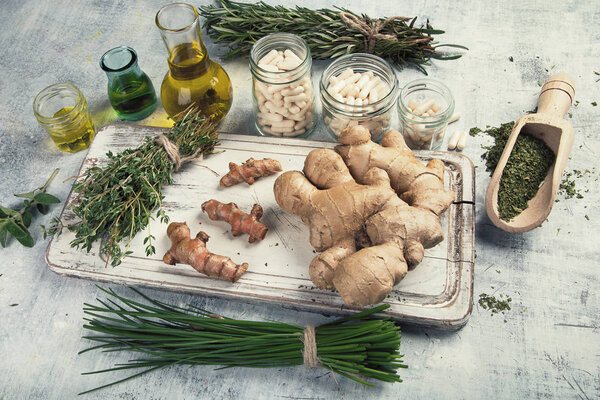 Healing herbs, essential oils and homeopathic pills on wooden tray