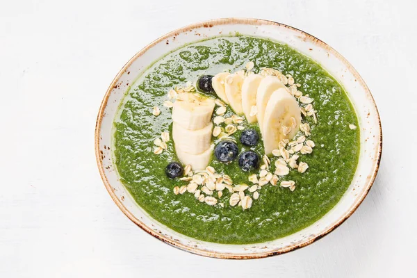 Green smoothie bowl with banana and fresh berries served in stylish bowl