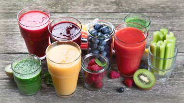 Ahşap arka planda farklı türde meyve püresi. Sağlıklı temiz ve detoks diyet yeme konsepti.