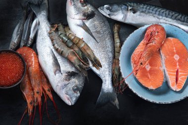 Siyah arka planda taze balık ve deniz ürünleri. Üst görünüm 