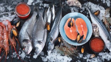 Siyah arka planda taze balık ve deniz ürünleri. Üst görünüm 