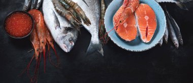 Siyah arka planda taze balık ve deniz ürünleri. Kopyalama alanı olan üst görünüm