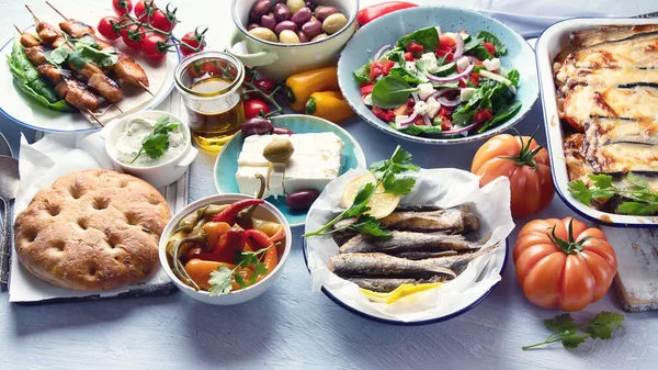 Greek food. Moussaka, meze, souvlaki, fish, pita, greek salad, tzatziki,  olives and vegetables. Traditional different types of greek dishes.