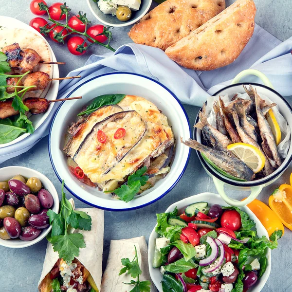 Greek food on grey background. Moussaka, gyros,souvlaki, pita, salad, olives and vegetables. Traditional different types of greek dishes. Top view