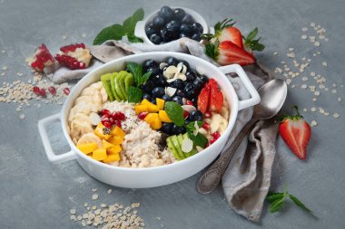 Böğürtlenli yulaf lapası ve gri arka planda meyve. Vitaminler ve antioksidanlarla sağlıklı kahvaltı.. 