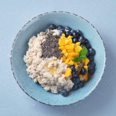 Sağlıklı kahvaltı için vitaminli ve antioksidanlı gri arka planda meyveli yulaf ezmesi lapası. Kopyalama alanı olan üst görünüm