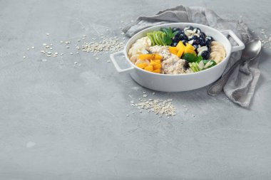 Böğürtlenli yulaf lapası ve gri arka planda meyve. Vitaminli ve antioksidanlı sağlıklı kahvaltı. Kopyalama alanı olan resim