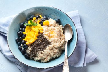 Sağlıklı kahvaltı için vitaminli ve antioksidanlı gri arka planda meyveli yulaf ezmesi lapası. Üst görünüm