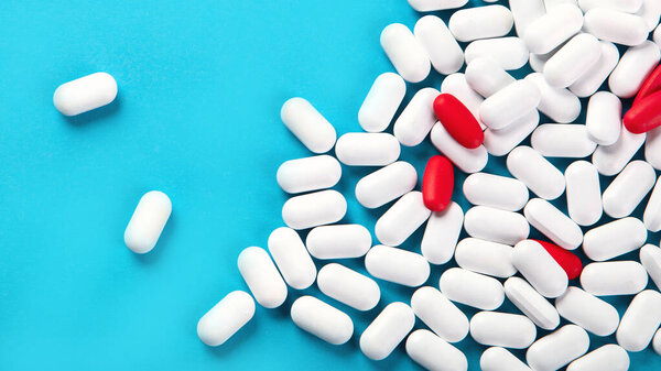 Heap of pills on blue background. Top view with copy space