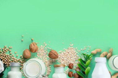 Süt ve malzeme bazlı çeşitli vejetaryen bitkileri. Yeşil renkli arka planda sütsüz içecekler. Sağlıklı vegan ve vejetaryen diyet kavramı. Kopyalama alanı olan üst görünüm