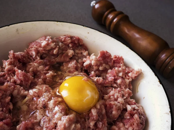 Viande hachée pour escalopes avec oeuf cru dans un bol en émail . — Photo